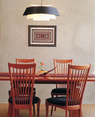 
This stuccoed wall adds to the earthiness of the dining room, broken by the ­softness of the centralized hanging light. The Barretts used dark colors in their home for this sense of the earth.

